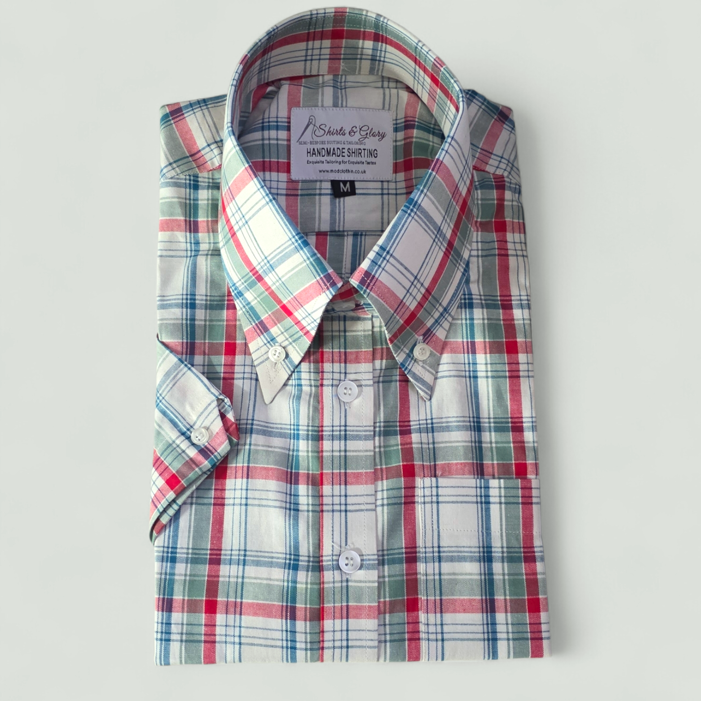 Checked shirt in red, green, blue, and white with a classic collar and branded tag reading “Shirts & Glory – Handmade Shirting.”
