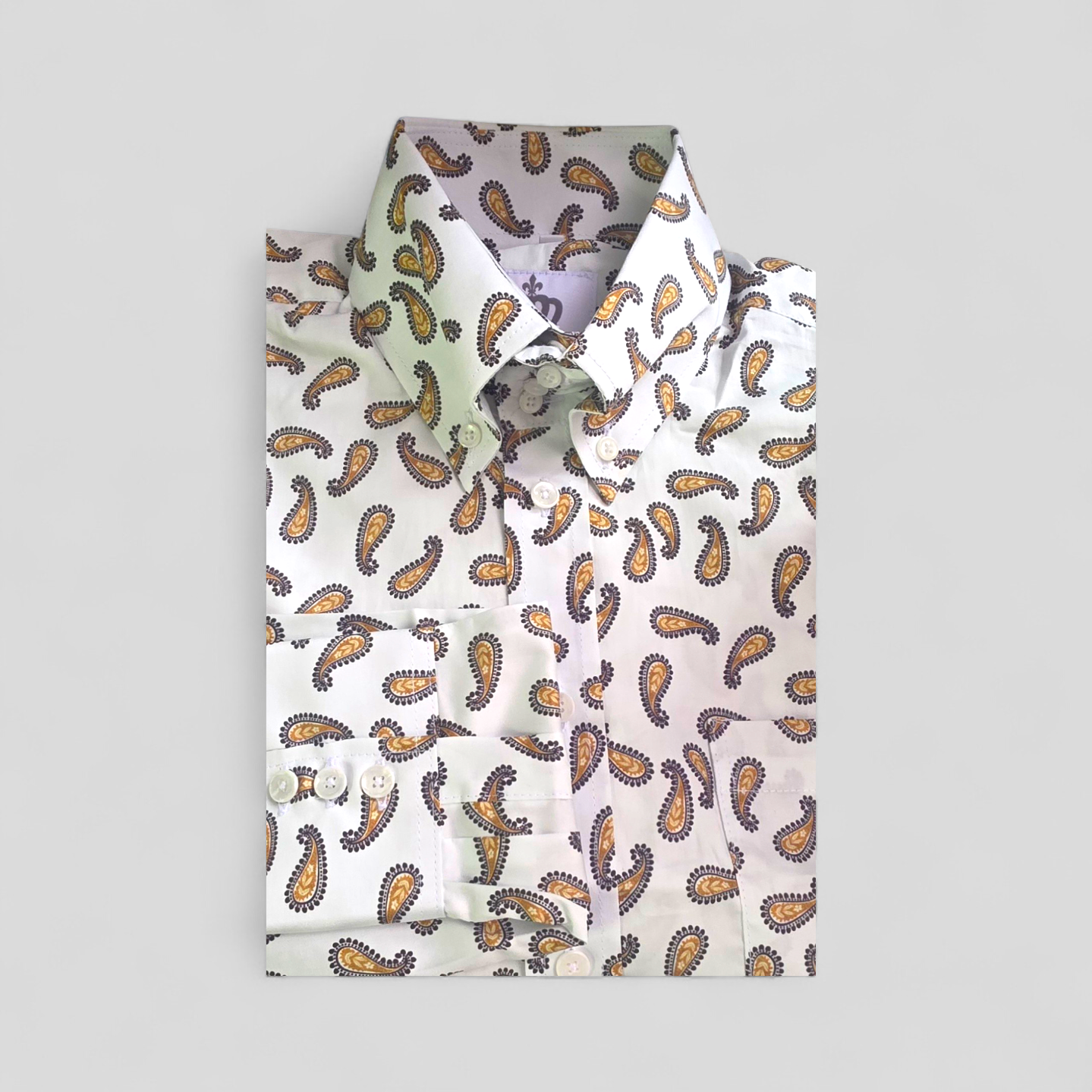 Folded long-sleeve paisley shirt with white buttons and classic collar.