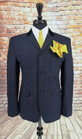 Ernest suit jacket on mannequin with velvet‑trimmed lapel and yellow accessories