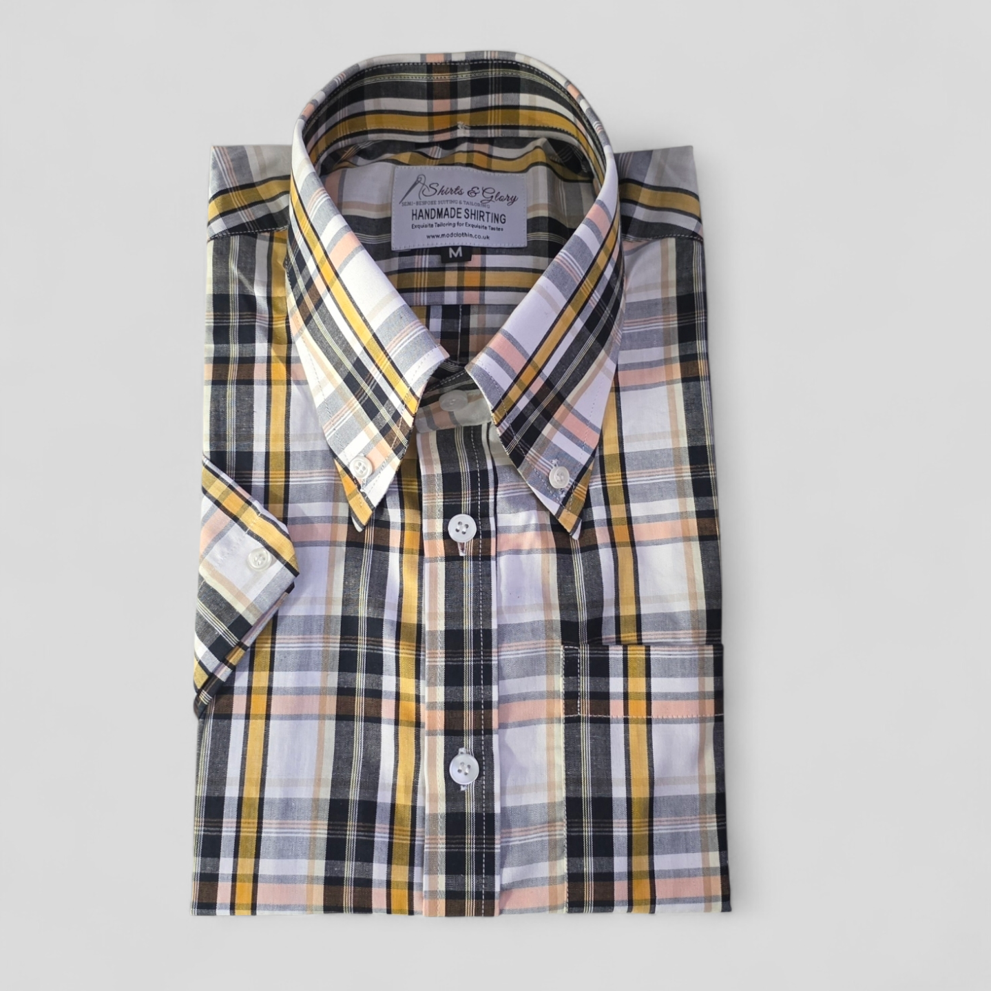 Folded multicoloured plaid shirt with white buttons and front pocket”